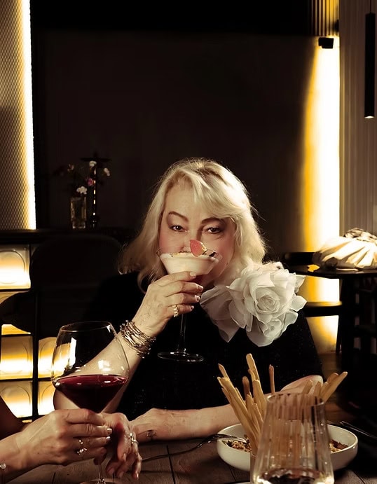 A woman enjoying a luxurious dinner at Villo Studio restaurant, sipping cocktail in elegant setting, perfect for fine dining and social gatherings.