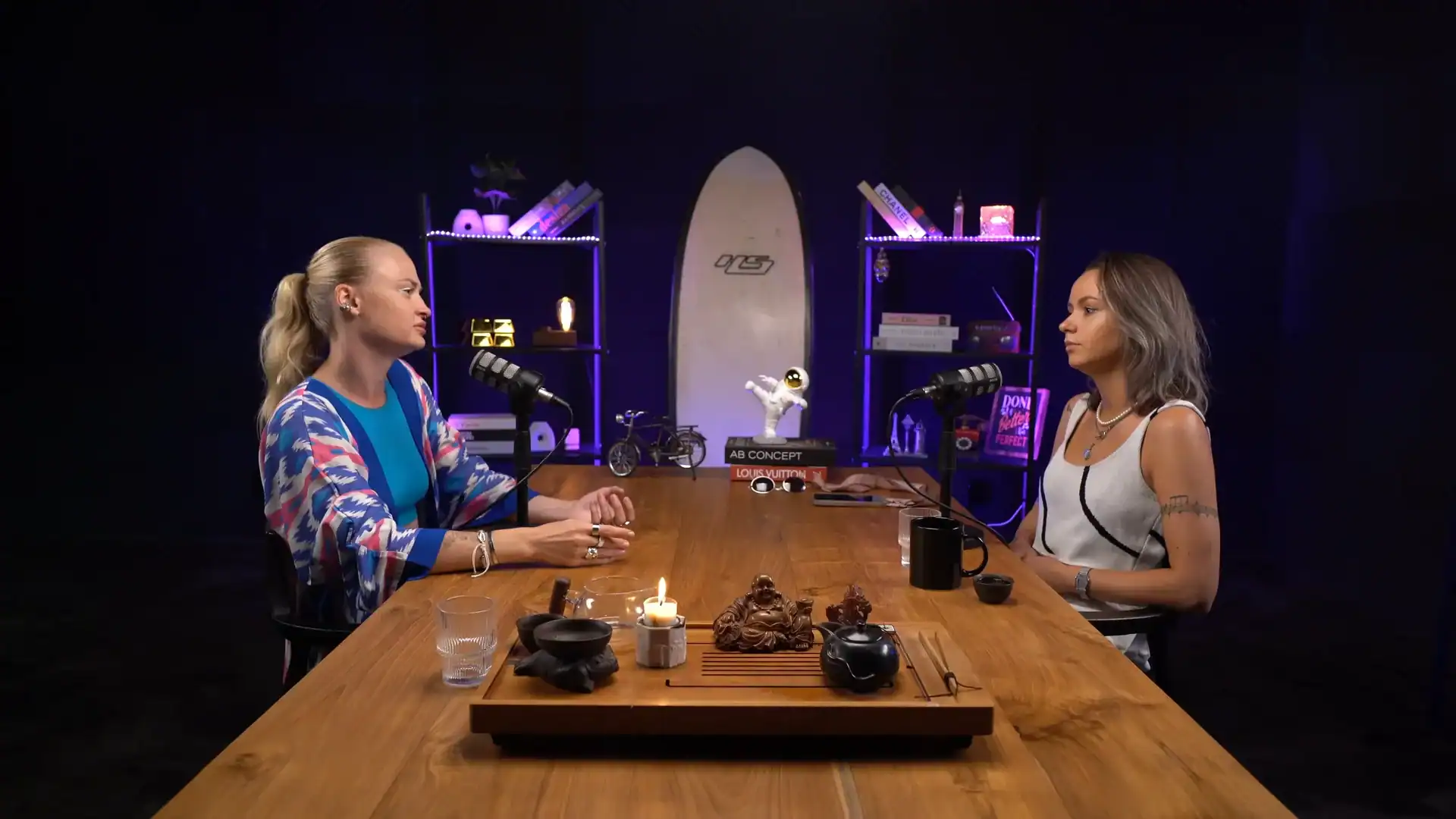 Women podcast hosts recording in a professional studio with modern decor and lighting.