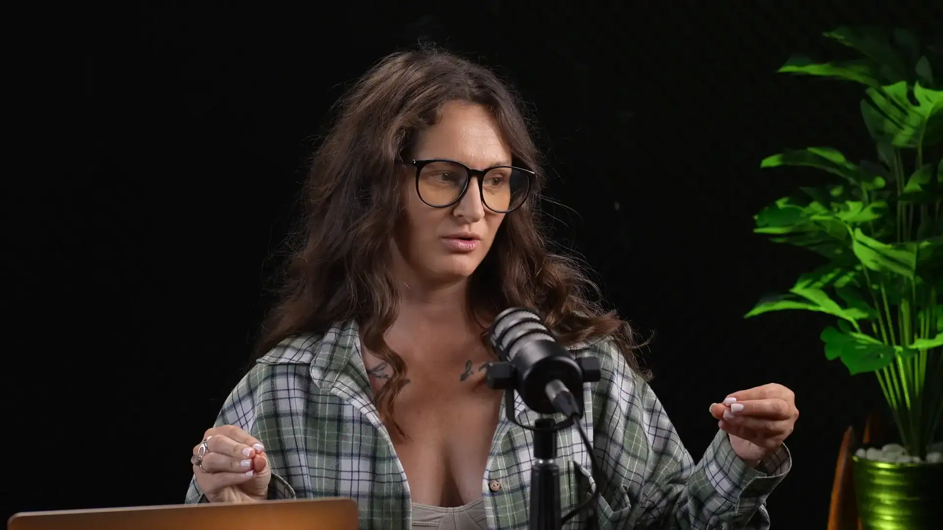 High-quality woman recording podcast in professional studio with microphone and green plant, modern podcast setup.