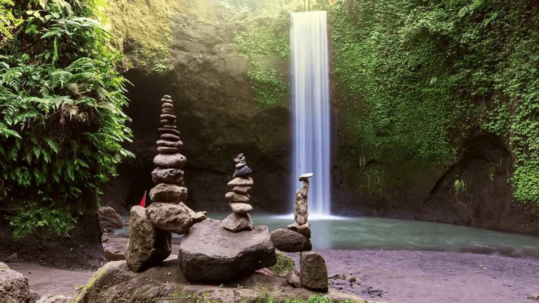 Beautiful waterfall cascading into a jungle pool surrounded by lush tropical greenery in Bali.