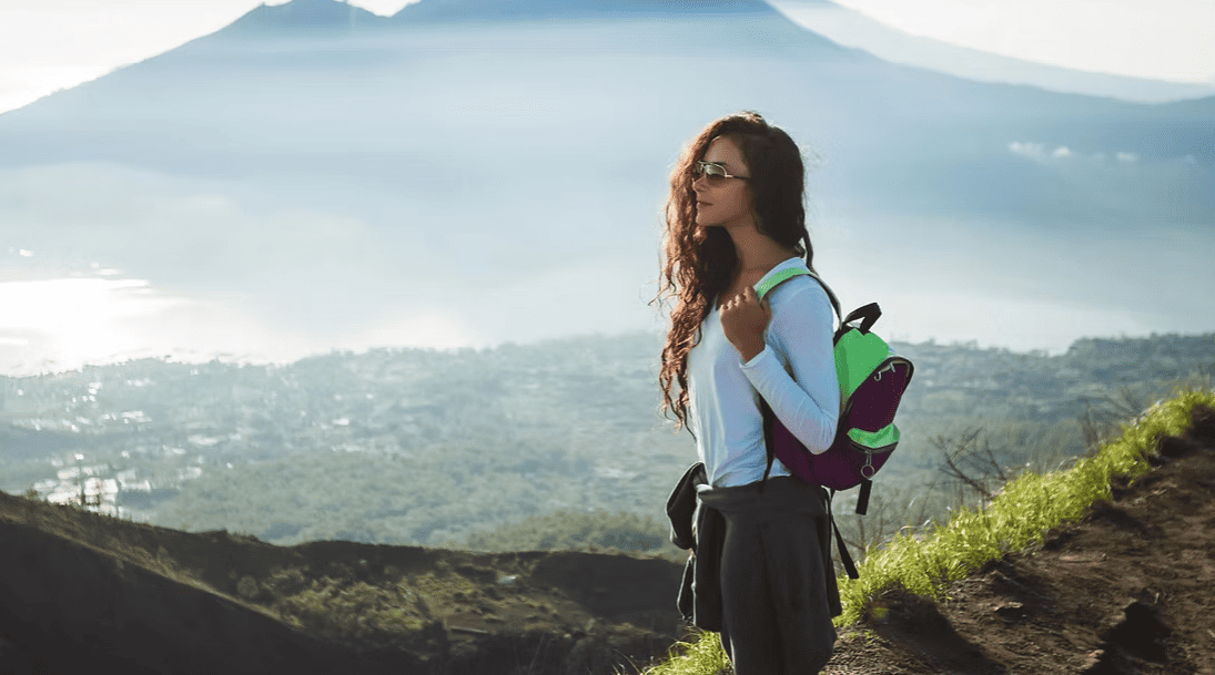Breathtaking mountain hiking scene with woman carrying a backpack and enjoying nature.
