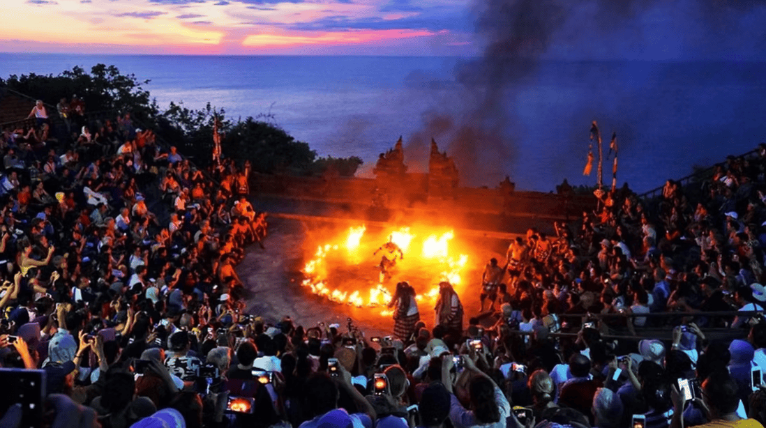 Colourful traditional Kecak dance performance at sunset on a cliff overlooking the Indian Ocean in Bali.