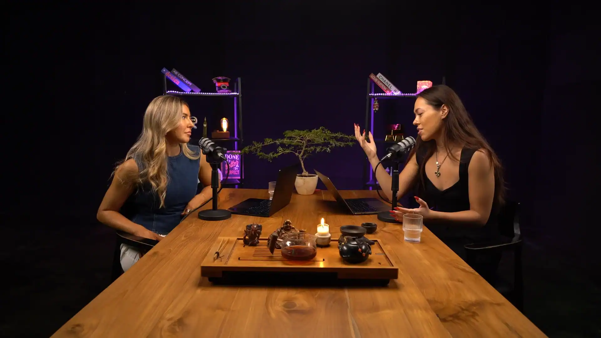 Professional podcast recording studio with two women engaged in conversation, modern decor, and audio equipment.